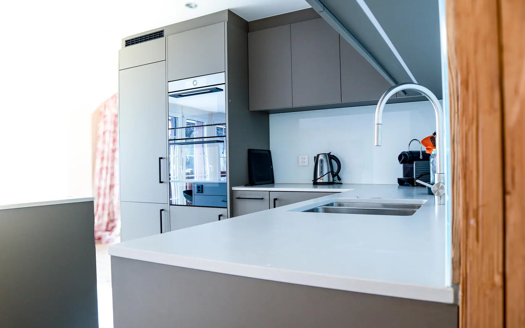 Küche mit matten, hellgrauen Fronten und schwarzen Griffen.