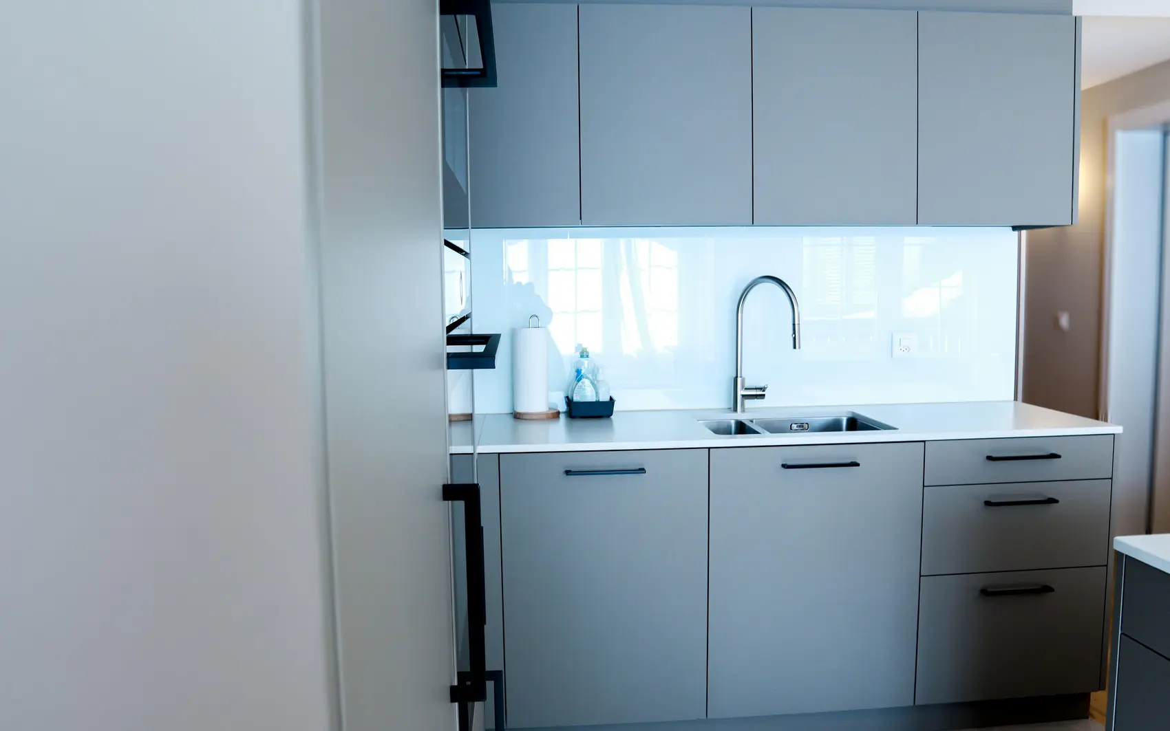 Küche mit matten, hellgrauen Fronten und schwarzen Griffen.