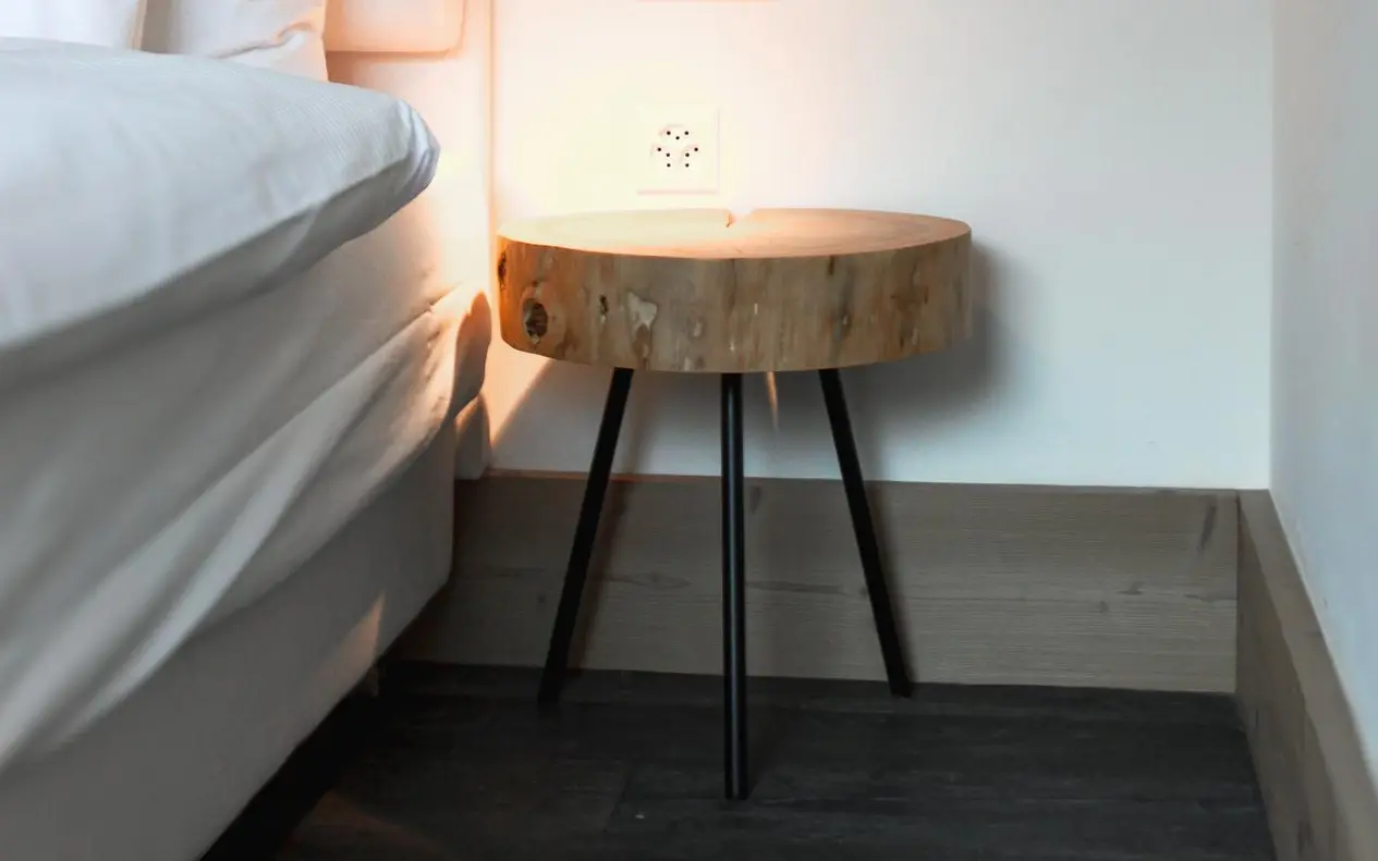 Nachttisch aus Holzstamm mit schwarzen Beinen.
