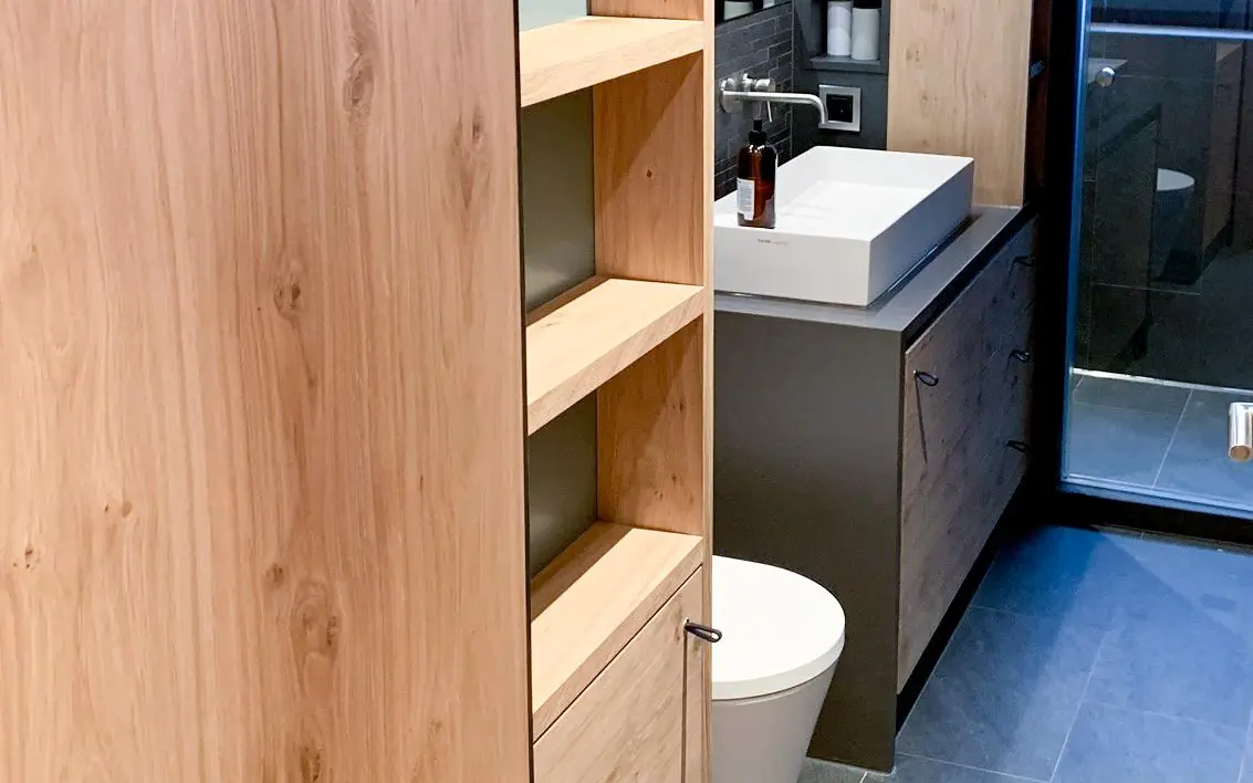 Badezimmereinrichtung aus Holz mit schwarzen Lederriemen als Schubladengriffe.