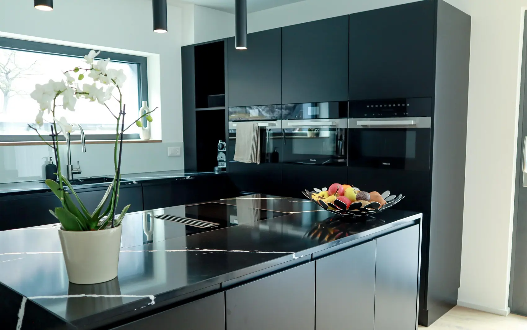 Küche mit mattschwarzen Fronten und Küchengeräten.