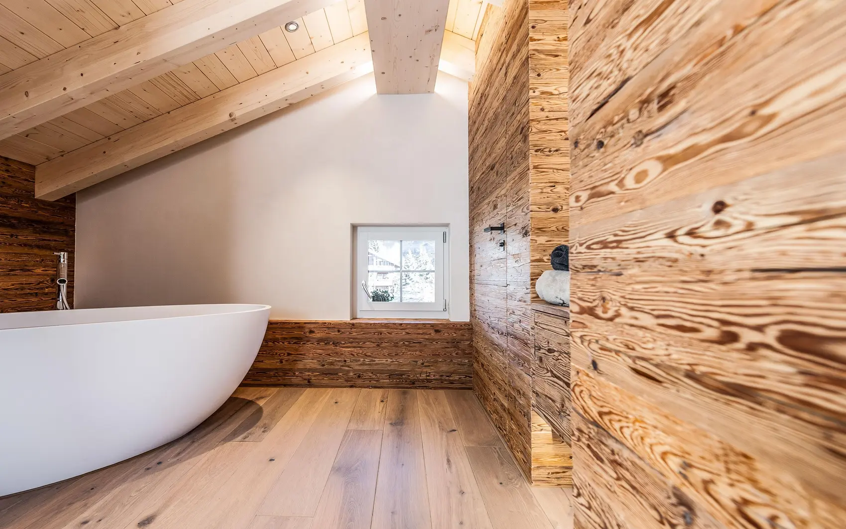 Badezimmer unter Dachschräge mit Wandholzverkleidung.